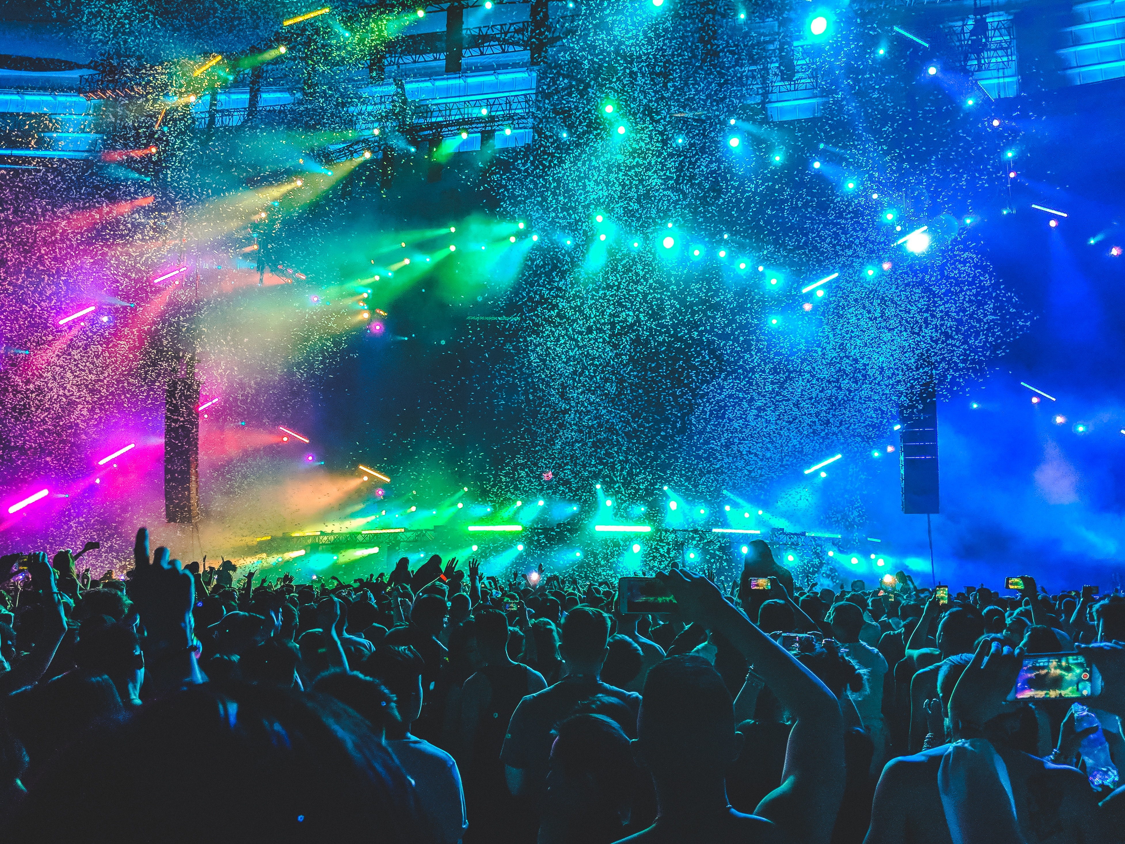 Stor konsertscene med konfetti og masse lys, tatt fra punlikumsperspektiv.