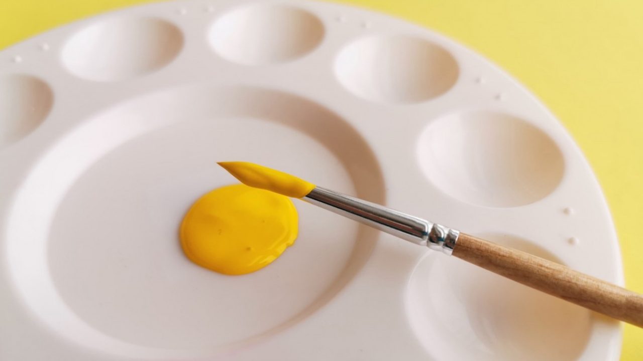Malepalett med gul farge og pensel med gul maling
