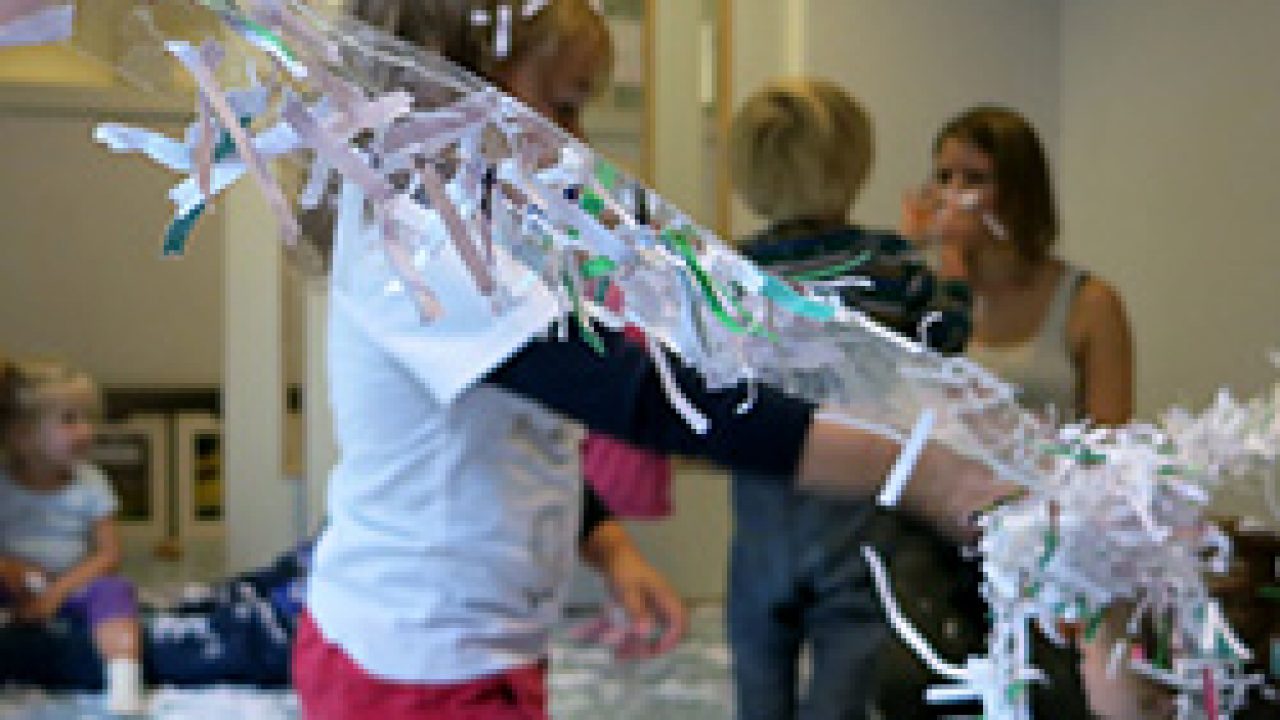 Barn henger opp papirstrimler på limbånd