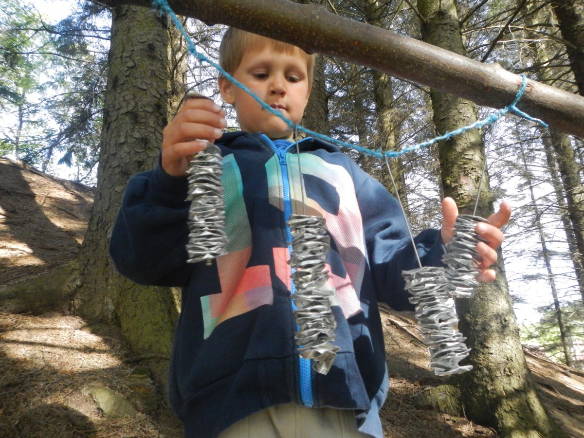 Gutt utforsker gjenbruksmateraler som henger i skogen.