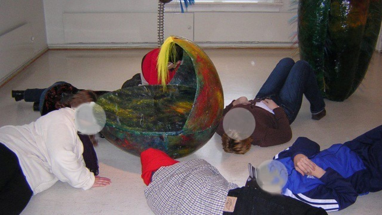 Elever ligger på gulvet og lytter rundt et rede av ull