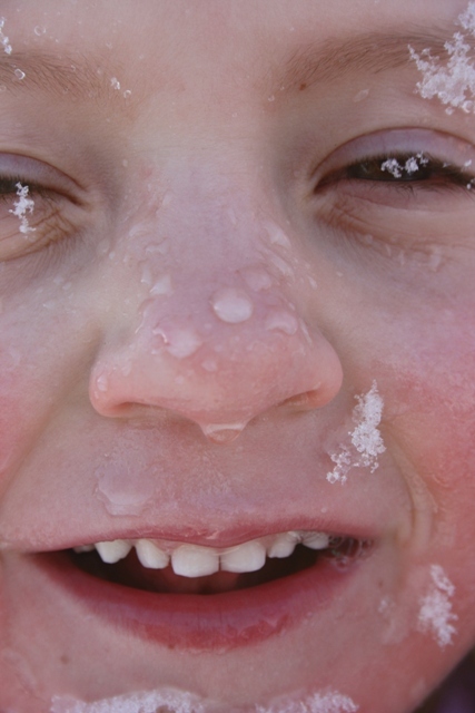Snø smelter i ansiktet på en gutt.