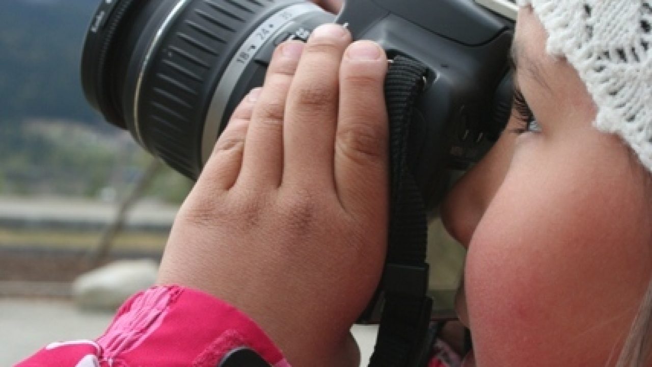 Barn fotograferer med speilreflekskamera.