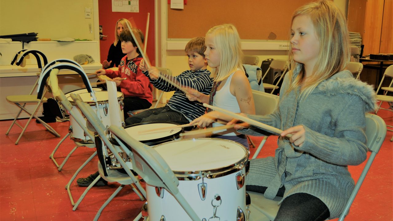 Barn som sitter og spiller trommer.