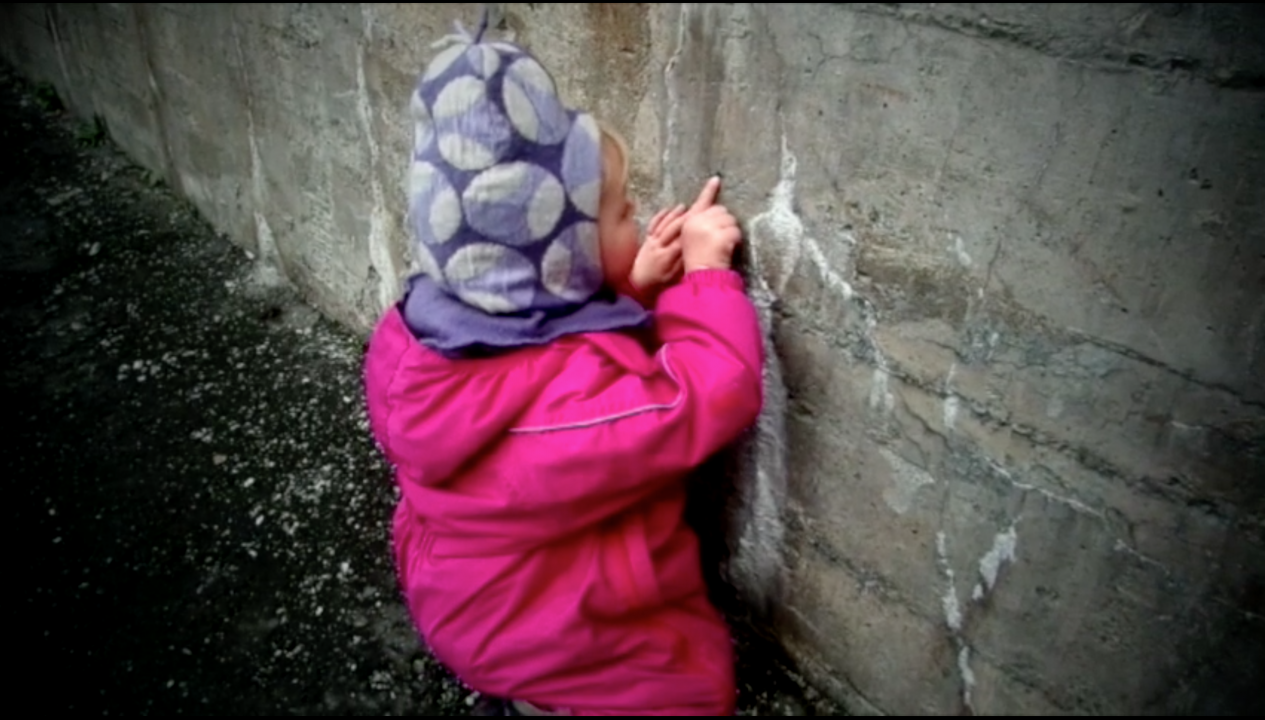 Jente utforsker hull i betongvegg.