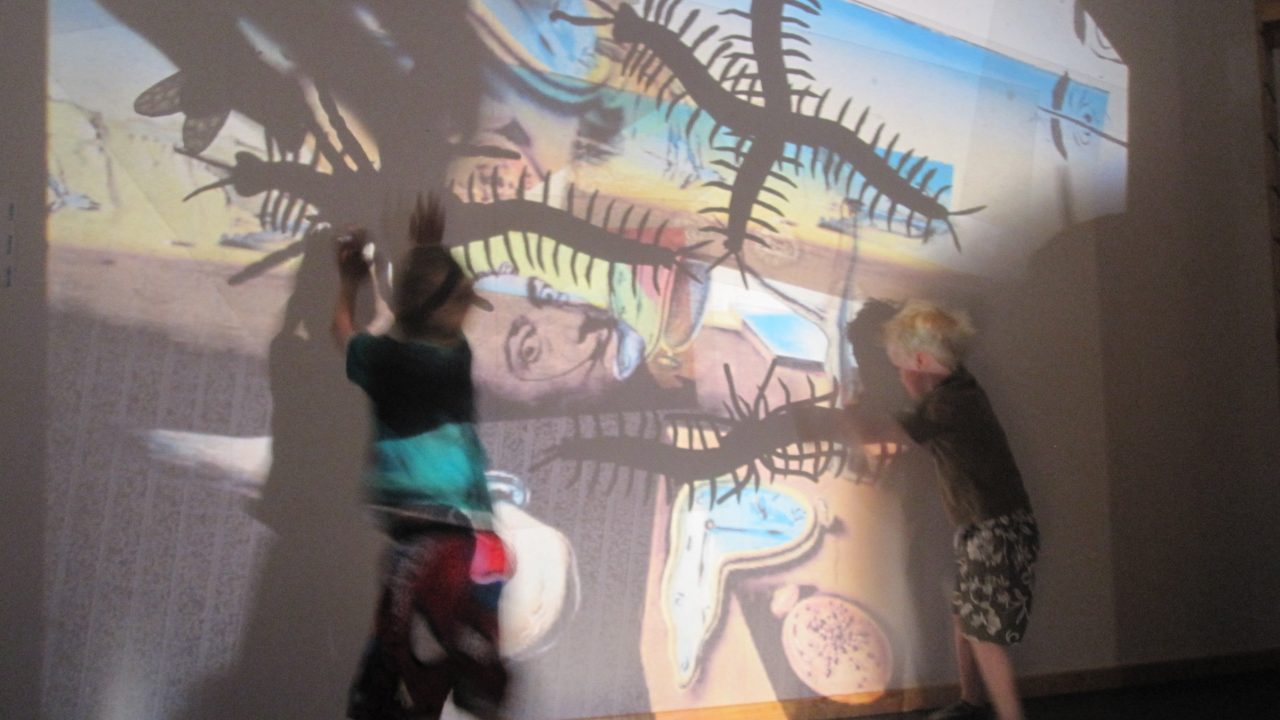 Barn som danser og eksperimenterer med lys mot vegg.
