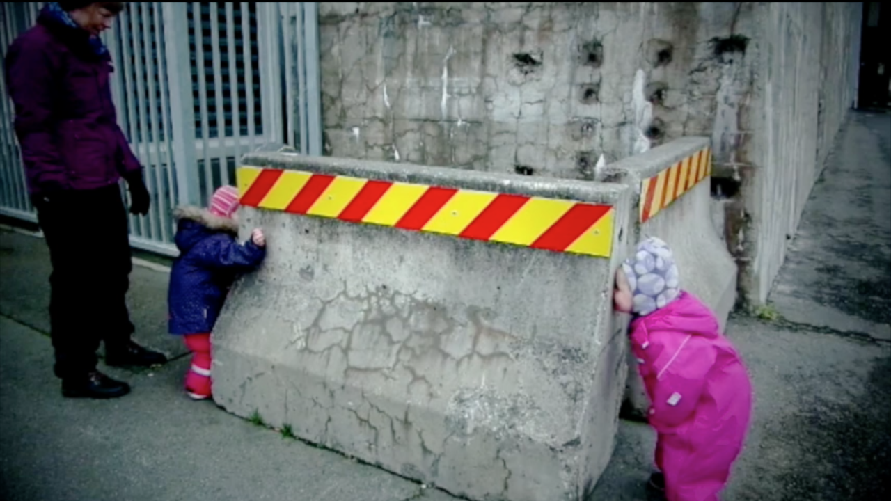 Barn titter gjennom hull i betongkloss.
