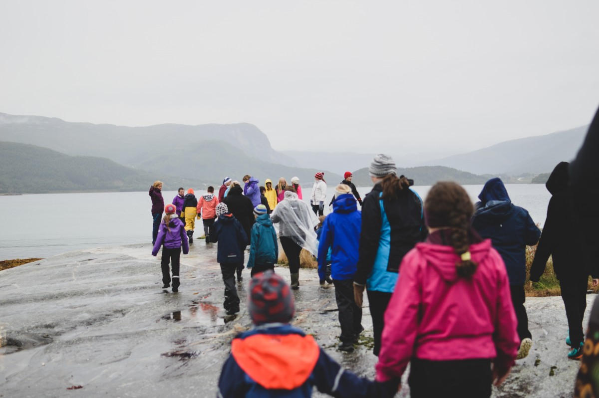Barn og voksne som går mot havet på berg.