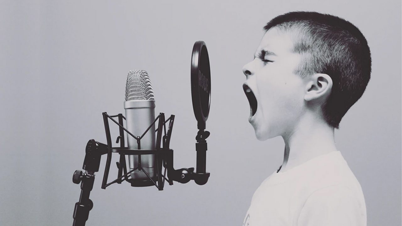 Gutt som synger i mikrofon.