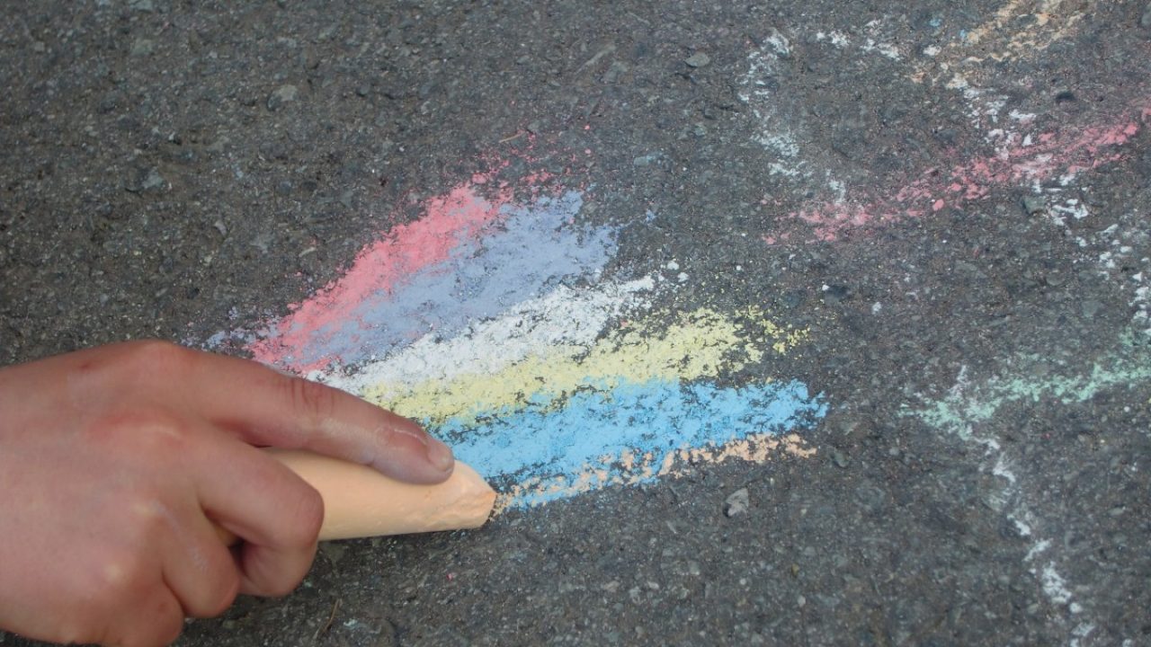 hånd som tegner med kritt på asfalt
