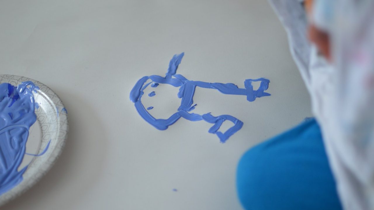 Barn bruker fingermaling og lager en blå figur. Foto av barns skapende prosess.