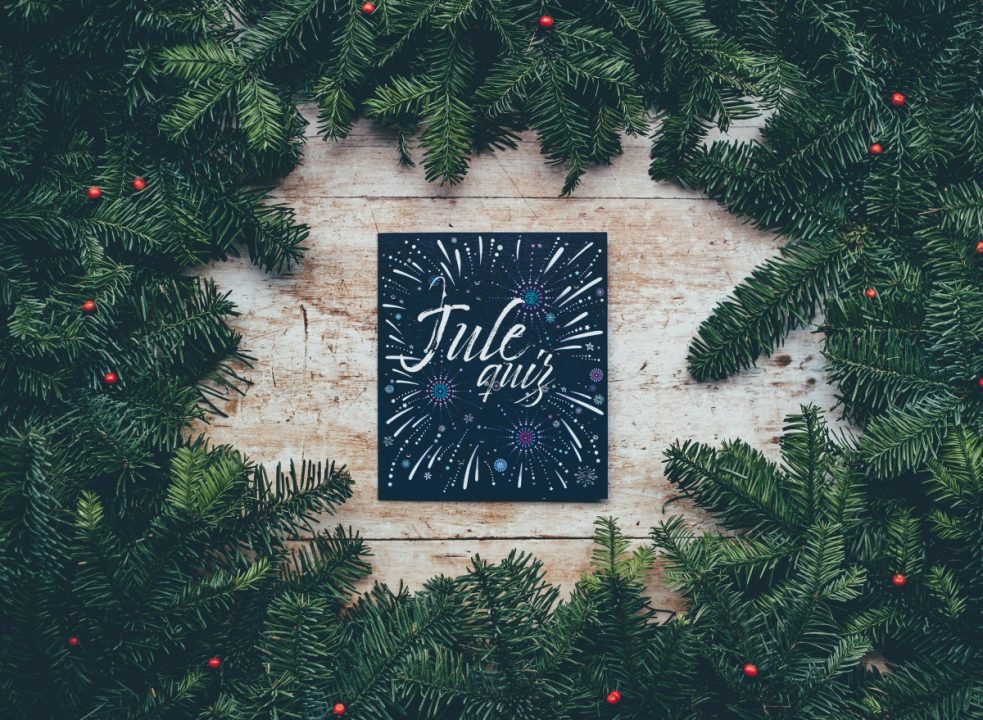 Illustrasjonsbilde med et julekort liggende mellom busker.