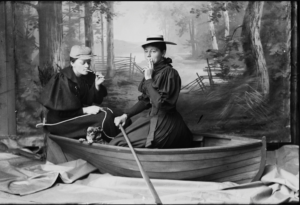To røykende kvinner i en robåt. Bildet er tatt innendørs.