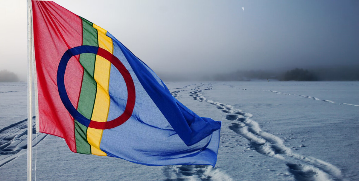 Snølandskap med spor. Samisk flagg i forgrunnen.