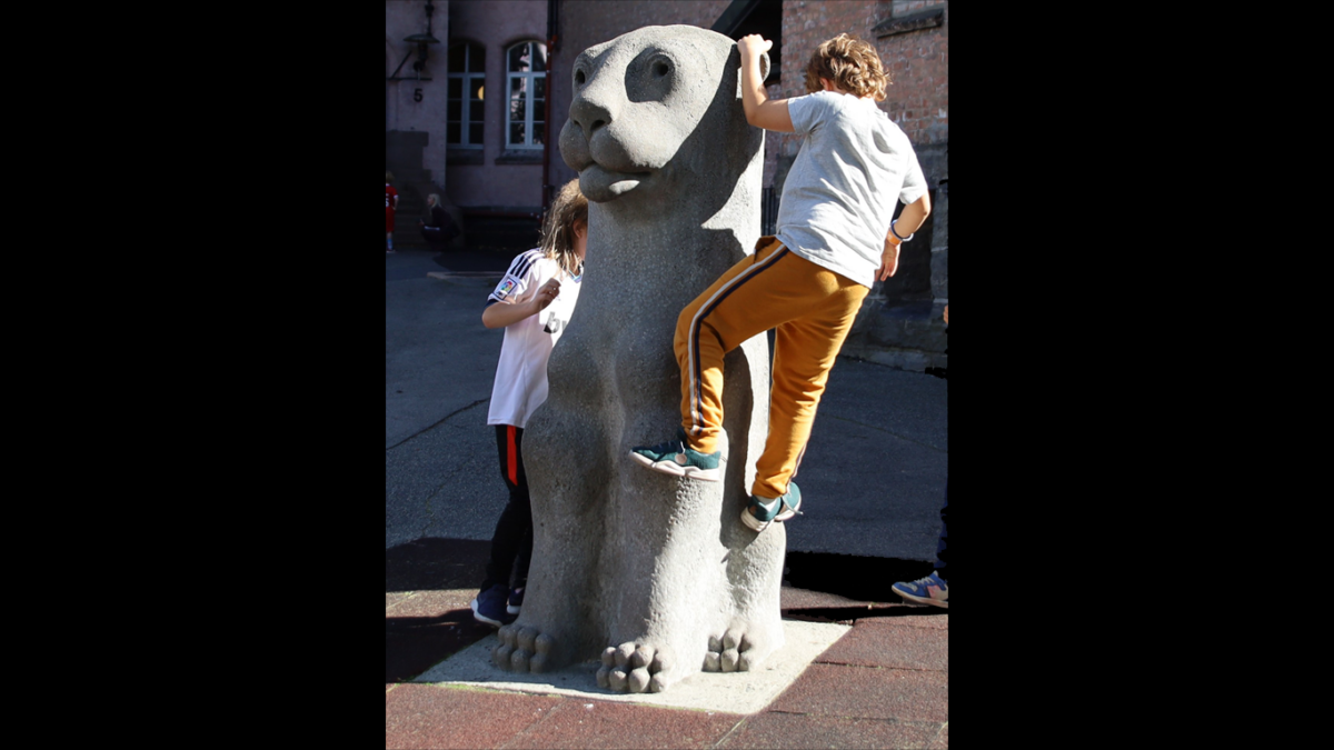 barn som klatrer på skulptur av løve